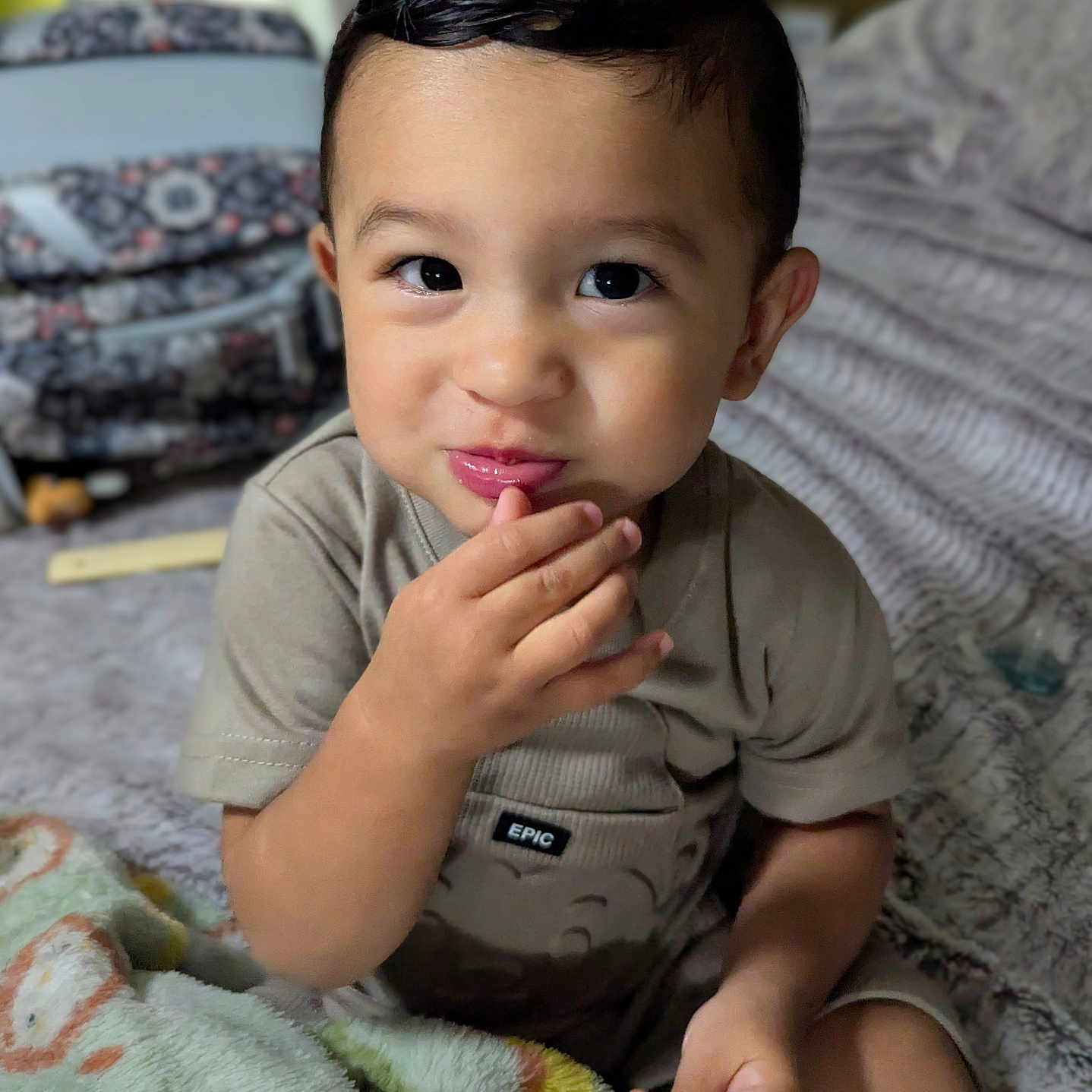 Lorenzo is registered to the contest to win money with this photo: bed, blanket, child, clothing, comfort, cozy, curly_hair, cute, expression, face, hand, indoor, person, portrait, sitting, skin, smile, snack, toddler, young_child