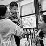 child, woman, smile, indoor, black_and_white, table, glass, napkins, bottle, furniture, holding, happy, people, portrait, casual, clothing, interaction, family, relaxation, candid