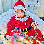 Shaurya is registered to the contest to win money with this photo: baby, blanket, child, christmas_lights, christmas_tree, cozy, cute, face, festive, headwear, holiday, holiday_decor, indoor, person, red_clothing, santa_claus_costume, seasonal, smiling, toddler, warm_lighting