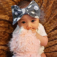 Lily joined the competition — help win amazing prizes! baby, child, infant, bow, headband, polka_dot, stuffed_animal, plush_toy, blanket, brown, pink, soft, cute, cuddling, lying_down, close_up, portrait, indoors, hand, eyes