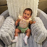 Lily is registered to the contest to win money with this photo: baby, child, smiling, sitting, fluffy_chair, plush, cushion, earrings, shorts, top, socks, happy, indoor, furniture, cozy, cute, portrait, infant, young_child, comfortable