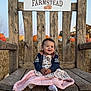 Lily is registered to the contest to win money with this photo: baby, child, smiling, wooden_chair, blanket, pumpkin, hay_bale, outdoor, fall, farmstead, dress, jacket, earrings, happy, portrait, sitting, nature, daylight, rustic, cute