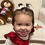 Lily is registered to the contest to win money with this photo: toddler, child, smiling, face, pigtails, hair_bow, earrings, red_dress, white_top, armchair, plush_toy, teddy_bear, cozy, indoor, cute, happy, baby, portrait, person, furniture
