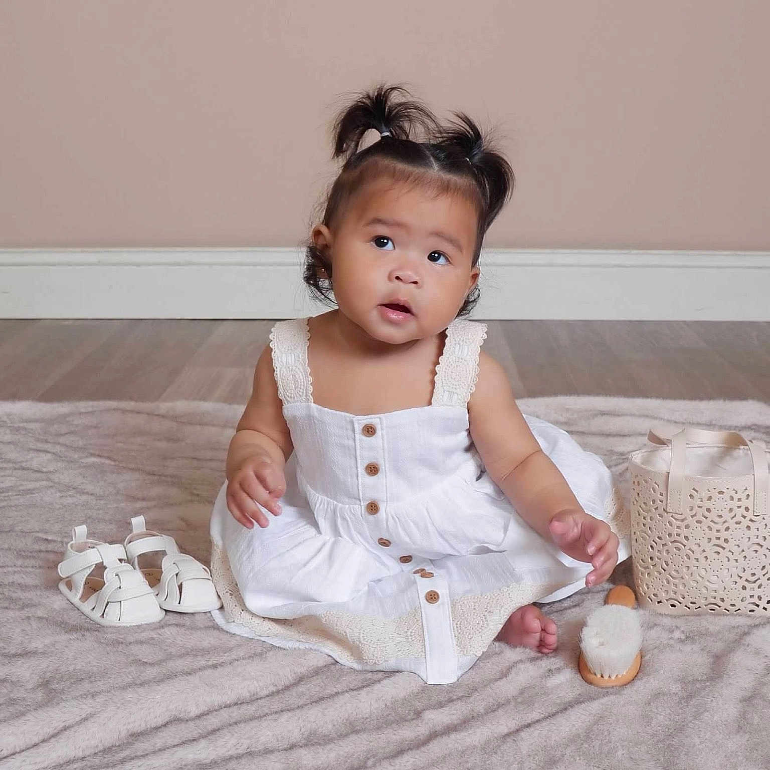 Kehlani is registered to the contest to win money with this photo: toddler, child, pigtails, white_dress, sandals, brush, basket, blanket, floor, wooden_floor, indoor, portrait, cute, sitting, baby, skin, face, expression, hair, clothing