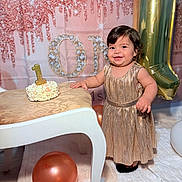 Gia joined the competition — help win amazing prizes! toddler, child, birthday, cake, candle, dress, gold, balloon, smile, celebration, party, table, floor, background, decorations, happy, indoors, person, festive, event