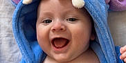 Raphaël Bouthors a rejoint le concours — aidez-le/la à gagner de superbes lots ! baby, blue_hoodie, purple_ears, smiling, happy, infant, cute, child, face, mouth_open, hand, soft_fabric, teeth_detail, hood, skin, lying_down, indoors, closeup, person, playful