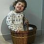basket, child, cozy, floor, hair, hands, happy, home, indoor, patterned_clothing, playful, portrait, shadow, sitting, smiling, sweater, teeth, toddler, wall, wicker_basket