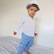 Pablo participe au concours pour gagner de l'argent avec cette photo : toddler, child, hat, fedora, white_shirt, polka_dots, blue_pants, barefoot, bed, bed_sheet, patterned_sheet, indoor, standing, portrait, person, cute, fashion, confident, smile, young_child