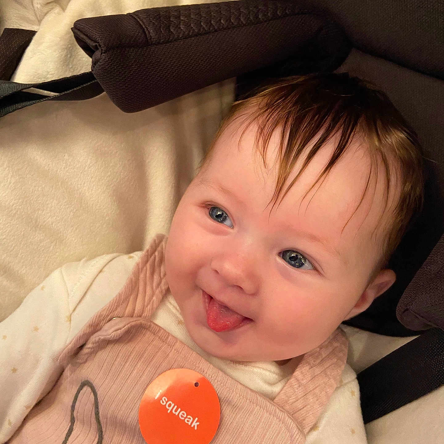 Savannah is registered to the contest to win money with this photo: apparel, baby, blue_eyes, child, closeup, cushion, cute, face, hair, happy, indoors, infant, person, pink_outfit, playful, seat, skin, smiling, tag, tongue_out