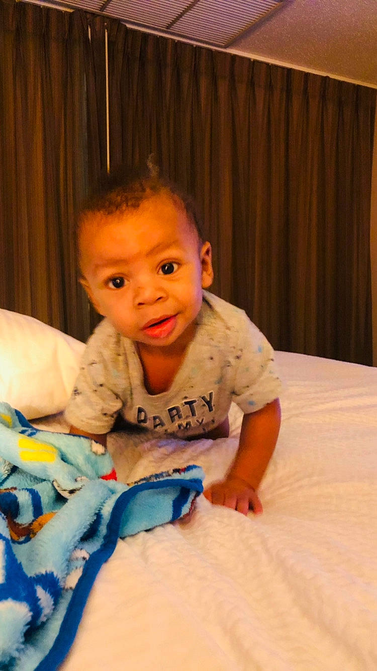 Destin is registered to the contest to win money with this photo: baby, baby_toddler_clothing, cheek, comfort, curtain, eye, face, finger, flooring, fun, happy, head, iris, mouth, neck, nose, person, sleeve, surprise, t_shirt