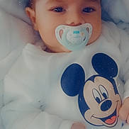 François participe au concours pour gagner de l'argent avec cette photo : baby, pacifier, mickey_mouse, onesie, infant, blanket, clothing, cute, face, hand, child, portrait, sleepwear, soft, comfort, lying_down, young_child, resting, indoors, adorable