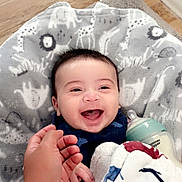 Zion joined the competition — help win amazing prizes! baby, smiling, laughing, hand, bottle, blanket, animal_print, floor, carpet, indoor, child, happy, cute, infant, person, clothing, holding_hand, baby_bottle, soft_texture, cozy