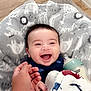 baby, smiling, laughing, hand, bottle, blanket, animal_print, floor, carpet, indoor, child, happy, cute, infant, person, clothing, holding_hand, baby_bottle, soft_texture, cozy