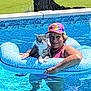 animal, blue, cat, colorful_cap, floating, inflatable_ring, leisure, outdoor, pattern, person, pet, pool, relaxation, smiling, summer, sunny, swimming, tabby_cat, vacation, water