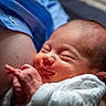 newborn, baby, infant, sleeping, smiling, closeup, face, hand, skin, blanket, clothing, adult, holding, comfort, tenderness, portrait, indoors, warm_light, peaceful, resting