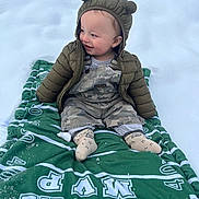 Mccally joined the competition — help win amazing prizes! baby, child, snow, green_blanket, jacket, hood, ears, smile, happy, outdoor, winter_clothing, camouflage_overalls, socks, sitting, blanket, cold_weather, cute, infant, person, nature