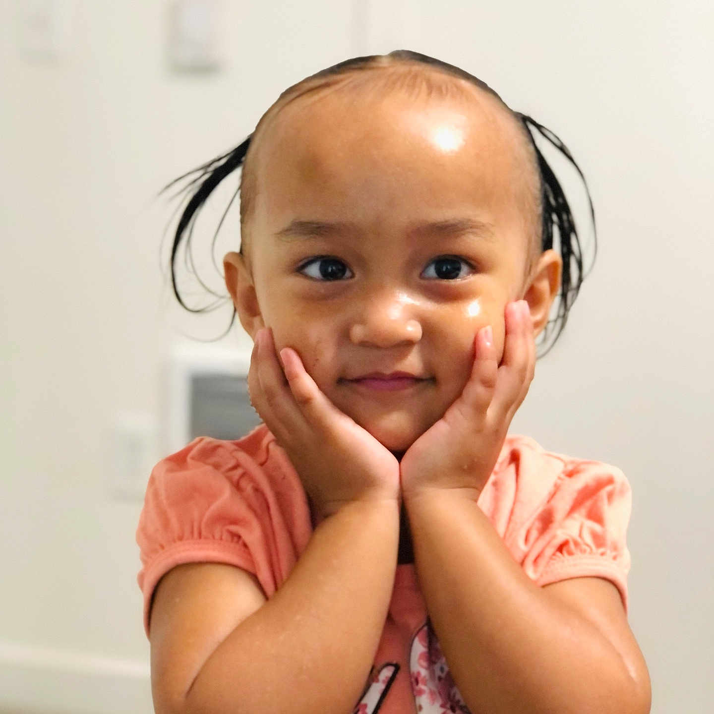 Juminah is registered to the contest to win money with this photo: child, toddler, portrait, smiling, happy, face, eyes, hair, pigtails, hands, cheeks, pink_shirt, clothing, indoors, home, wall, close_up, cute, sitting, photography
