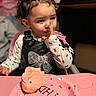 Nevayla joined the competition — help win amazing prizes! toddler, child, curly_hair, black_bow, birthday, cupcake, pink_frosting, plate, table, highchair, long_sleeve_shirt, black_overall, indoor, face, person, celebration, food, cute, expression, party
