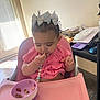 baby, child, high_chair, pink, bow, snack, bowl, food, indoor, table, clothing, person, cute, curly_hair, earrings, beads, furniture, window, light, floor
