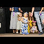 toddler, child, laughing, blue_and_white_outfit, headband, stage, people, adults, children, dress, ribbons, smiling, casual_clothing, happy, indoor, event, footwear, jeans, colorful_clothing, celebration