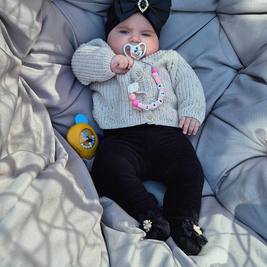 Karla is registered to the contest to win money with this photo: baby, bed, blanket, bonnet, cap, clothing, couch, cushion, face, furniture, glove, hat, head, homedecor, knitwear, pants, person, photography, portrait, sweater