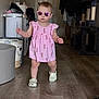 baby, basket, cat_tree, child, crocs, cute, door, fashion, floor, footwear, home, indoor, person, pink_dress, short_hair, summer_clothing, sunglasses, toddler, walking, wooden_floor