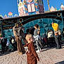 Ethan participe au concours pour gagner de l'argent avec cette photo : child, toddler, costume, amusement_park, stroller, adult, pavement, building, blue_sky, sunlight, outdoor, people, playful, casual_clothing, family, daytime, shadow, fun, waiting, park