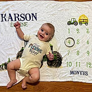 Karson joined the competition — help win amazing prizes! baby, infant, smiling, onesie, blanket, milestone_blanket, numbers, months, ring, wooden_floor, face, child, happy, lying_down, baby_clothing, personalized_blanket, tractor, cute, portrait, indoor