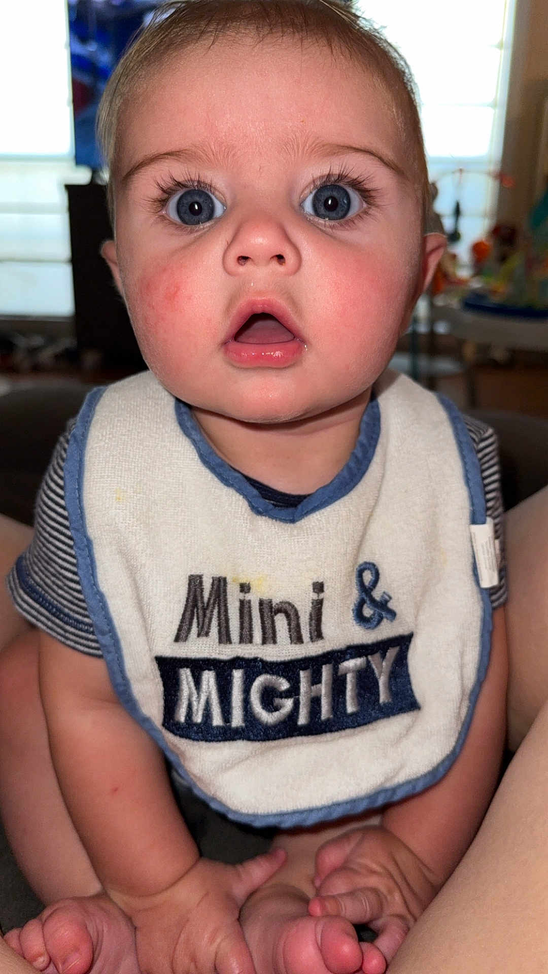 Karson joined the competition — help win amazing prizes! baby, infant, bib, blue_eyes, chubby, cute, expression, face, hands, feet, indoor, person, portrait, skin, sitting, striped_shirt, text_on_bib, young_child, wide_eyes, close_up