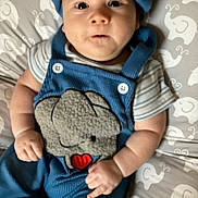 Damian is registered to the contest to win money with this photo: baby, infant, blue_clothing, elephant_design, blanket, pattern, face, hands, cute, lying_down, wide_eyes, curious_expression, striped_shirt, headwear, soft_toys, child, indoors, closeup, infant_clothing, baby_outfit