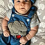 baby, infant, blue_clothing, elephant_design, blanket, pattern, face, hands, cute, lying_down, wide_eyes, curious_expression, striped_shirt, headwear, soft_toys, child, indoors, closeup, infant_clothing, baby_outfit