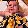 Alanni is registered to the contest to win money with this photo: baby, child, smiling, headband, sunflower_pattern, clothing, bare_skin, arms_outstretched, lying_down, blanket, cute, infant, happy, portrait, face, head, expression, soft_lighting, closeup, indoors