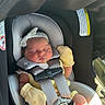 baby, newborn, car_seat, sleeping, infant, mittens, headband, child, safety_harness, foot, seatbelt, sunlight, cute, indoors, child_seat, peaceful, person, baby_clothes, car_interior, resting