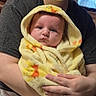 baby, infant, child, caregiver, portrait, indoors, blanket, yellow_blanket, hooded_blanket, sitting, held, face, smiling, eyes, hands, family, home, television, photography, safe