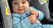 Corey is registered to the contest to win money with this photo: baby, child, infant, car_seat, car, portrait, hat, beanie, pom_pom, blue_clothing, striped_pajamas, sitting, indoors, vehicle,  안전, smiling, face, hands, cozy, travel