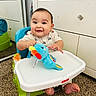 Corey joined the competition — help win amazing prizes! baby, child, infant, smiling, happy, high_chair, toy, elephant_toy, blue_toy, pacifier, kitchen, cabinets, carpet, indoor, portrait, sitting, hands, feet, colorful, playtime