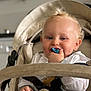 Farel participe au concours pour gagner de l'argent avec cette photo : baby, blond_hair, pacifier, stroller, child, infant, cute, smiling, happy, face, hand, clothing, seatbelt, indoors, portrait, young_child, curly_hair, person, comfortable, closeup