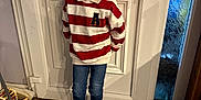 Swann participe au concours pour gagner de l'argent avec cette photo : child, boy, smile, standing, door, white_door, striped_sweater, red_and_white, jeans, sneakers, floor, wood_floor, indoor, home, broom, mop, window, frosted_glass, happy, casual