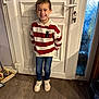 child, boy, smile, standing, door, white_door, striped_sweater, red_and_white, jeans, sneakers, floor, wood_floor, indoor, home, broom, mop, window, frosted_glass, happy, casual