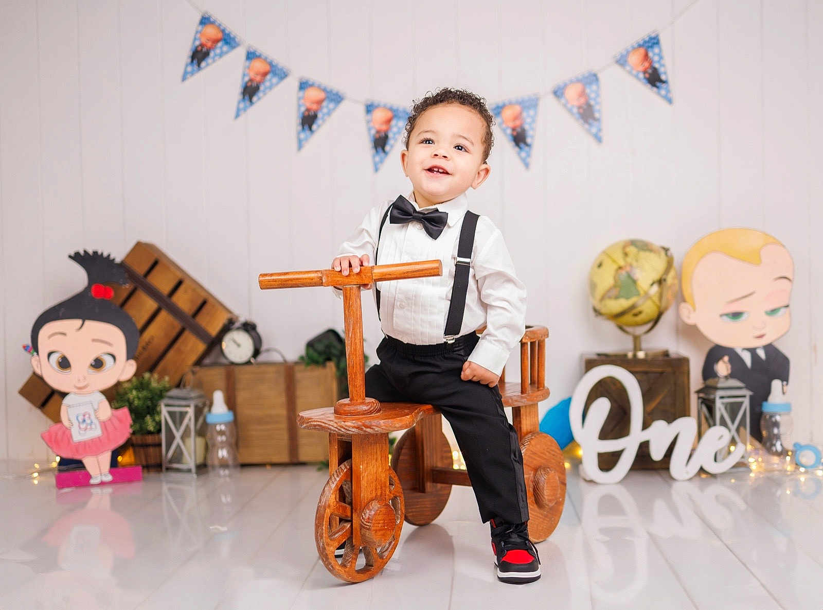 Theon joined the competition — help win amazing prizes! toddler, child, wooden_tricycle, bow_tie, suspenders, birthday, party_decorations, cartoon_cutouts, floor_reflection, smiling, indoors, celebration, toy, white_shirt, black_pants, sneakers, globe, lantern, gift_box, banner
