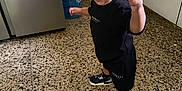 Theon joined the competition — help win amazing prizes! toddler, child, black_clothing, sneakers, curly_hair, indoor, kitchen, water_dispenser, floor_tiles, cabinet, expression, motion, young_child, person, standing, black_shorts, black_tshirt, playful, happy