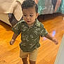 Theon joined the competition — help win amazing prizes! toddler, child, indoor, wooden_floor, bed, blanket, green_shirt, shorts, sandals, curly_hair, walking, person, floor, home, furniture, blurred_background, cute, young_child, casual_clothing, portrait