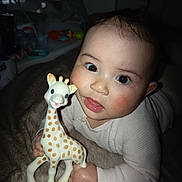 Luna a rejoint le concours — aidez-le/la à gagner de superbes lots ! baby, big_eyes, blanket, cheeks, child, close_up, cute, flash_photography, giraffe_toy, hand, indoor, infant, lying_down, nursery, onesie, portrait, rosy_cheeks, smile, teething_toy, toy