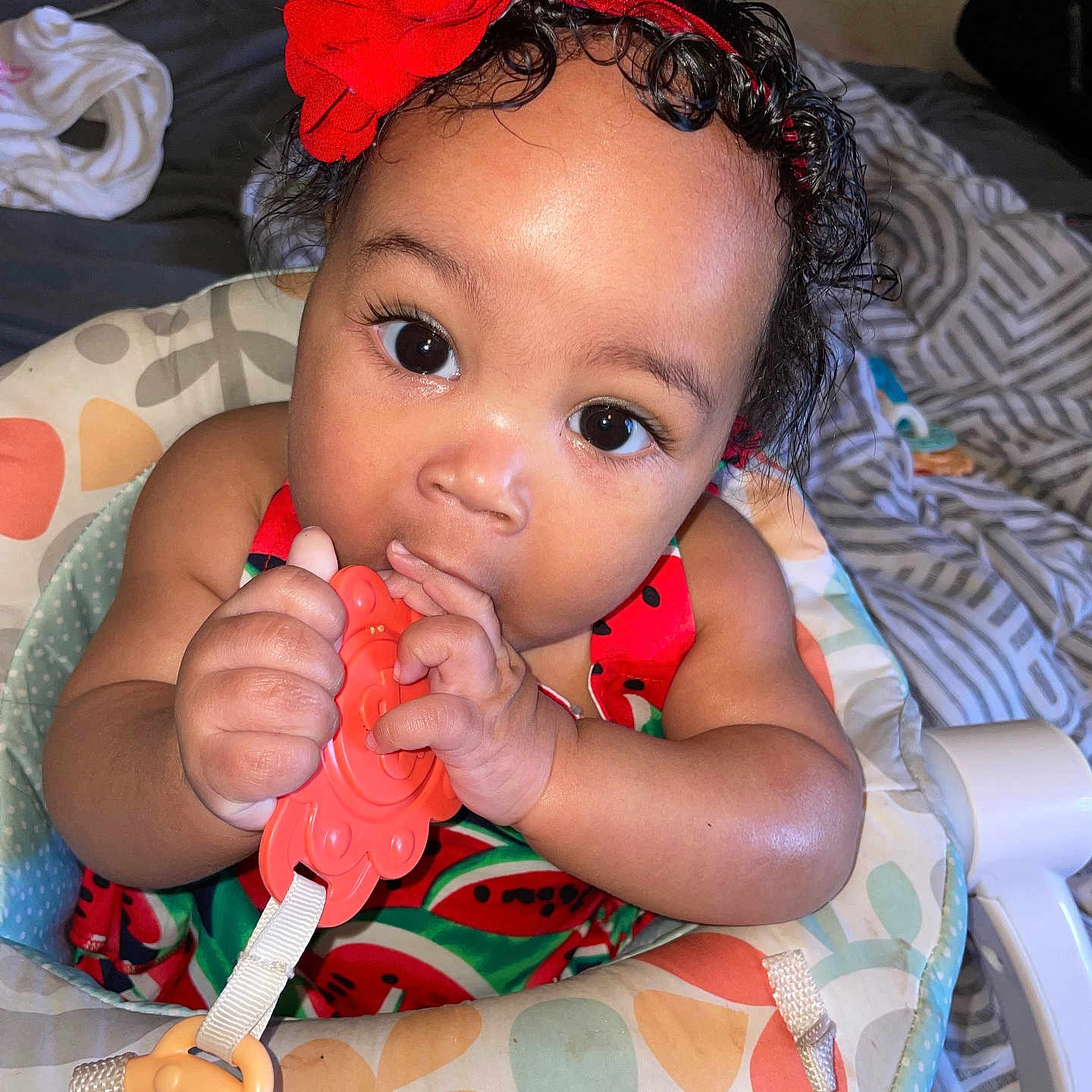 Laihani joined the competition — help win amazing prizes! baby, baby_seat, big_eyes, blanket, chewing, child, closeup, colorful_clothing, curly_hair, cute, face, hand, headband, indoor, infant, pattern, red_flower, skin, teether, toy