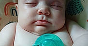 Riley joined the competition — help win amazing prizes! baby, sleeping, pacifier, polka_dot, cushion, rainbow, animal_print, infant, child, skin, hand, face, closeup, peaceful, rest, indoors, cute, soft_light, comfortable, portrait