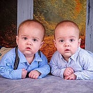 Côme Et Marceau a rejoint le concours — aidez-le/la à gagner de superbes lots ! baby, twin_babies, infant, portrait, studio, lying_down, blue_shirts, suspenders, pants, siblings, curious_expression, wide_eyes, hands, blanket, floor, backdrop, autumn_background, wood_pillars, photography, cute