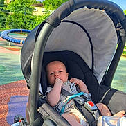 Nathanaël a rejoint le concours — aidez-le/la à gagner de superbes lots ! baby, canopy, casual_clothing, child, colorful_ground, daylight, footwear_free, greenery, infant, nature, outdoor, park, plastic_bottle, playground, relaxing, safety_harness, seatbelt, stroller, summer, sunlight
