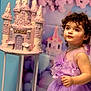 child, toddler, dress, lavender, cake, castle, birthday, party, curly_hair, face, blue_eyes, decoration, balloons, pink, pastel_colors, portrait, celebration, cute, standing, soft_focus
