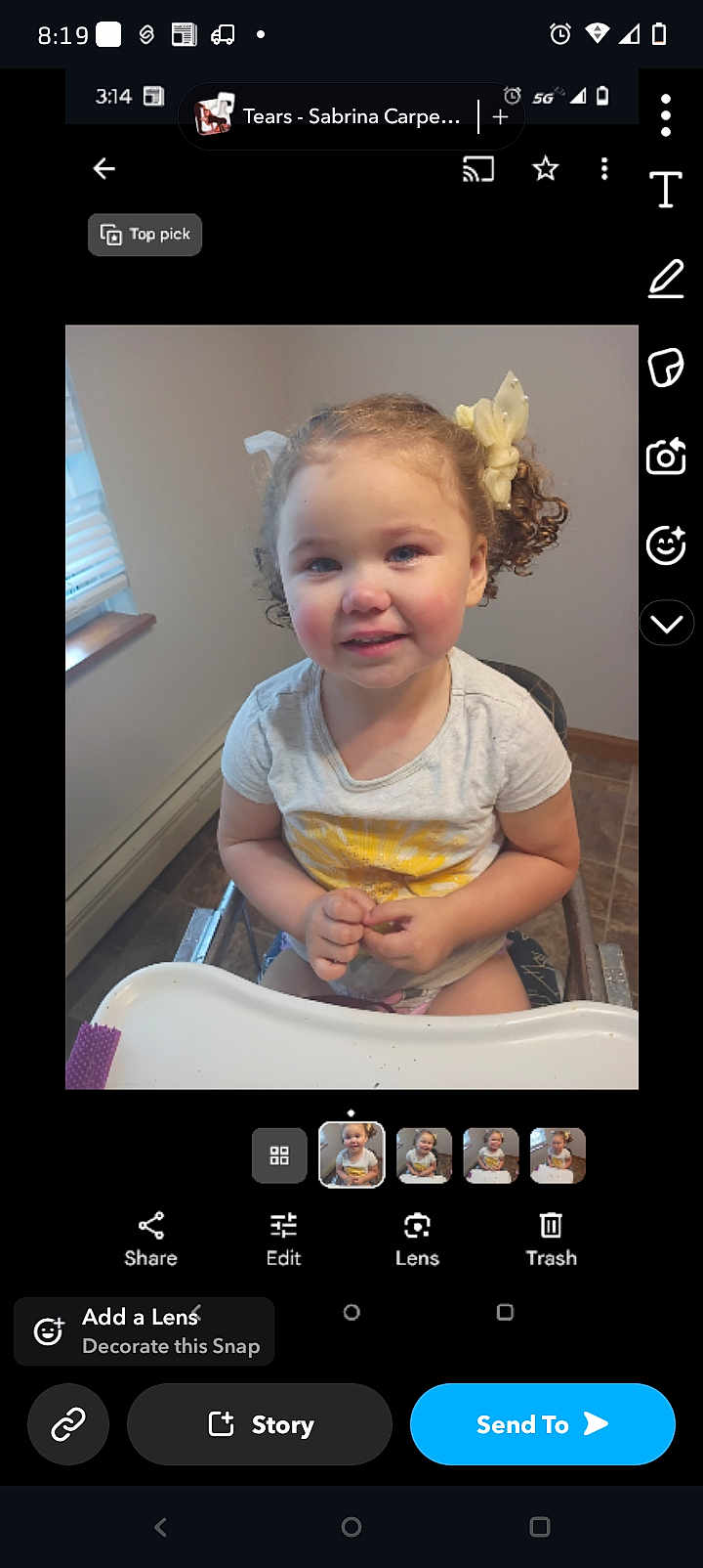 Nya Robbie is registered to the contest to win money with this photo: toddler, child, smiling, curly_hair, high_chair, indoor, window, white_tshirt, yellow_sun, hair_bows, hands, face, person, young_child, happy, seated, floor_tiles, natural_light, home, casual_clothing