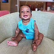 Johnathan joined the competition — help win amazing prizes! baby, child, smiling, blue_onesie, armchair, sitting, happy, indoors, portrait, cute, infant, skin, face, feet, hands, furniture, background_blur, expression, young, person